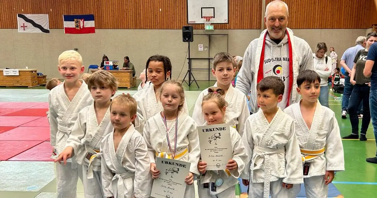 Eine Gruppe von Kindern posiert stolz mit ihren Judo-Gürteln für ein Foto